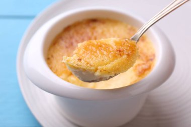 Açık mavi masada kaseden kaşıkla leziz bir creme brulee alıp yakın plan çekiyoruz.
