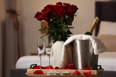 Balayı. Köpüklü şarap, bardak ve gül buketi odasındaki ahşap masada.