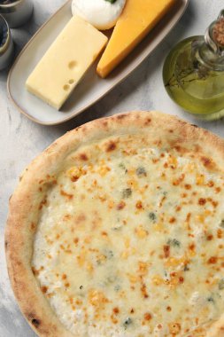 Lezzetli peynirli pizza, yağ ve çeşitli peynirler açık gri desenli masa, düz uzanma