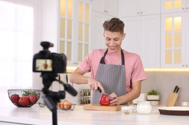 Mutfakta video kaydederken gülümseyen yemek blogcusu yemek pişiriyor