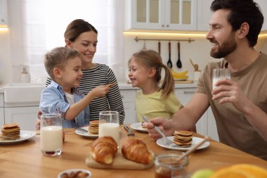 Mutlu bir aile mutfakta kahvaltı ederken eğleniyor.
