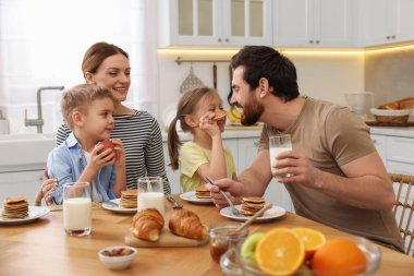 Mutlu bir aile mutfakta kahvaltı ederken eğleniyor.