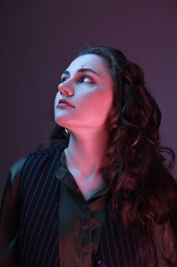 Renkli arka planda, neon ışıklı güzel bir genç kadının portresi
