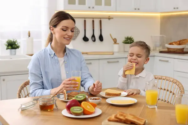 キッチンでテーブルで朝食を食べている母と彼女のかわいい小さな息子 — ストック写真