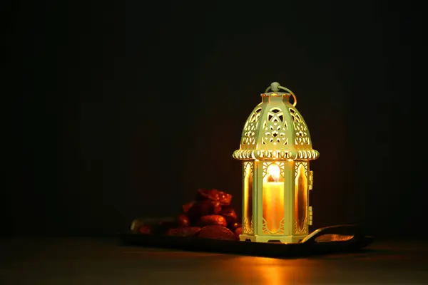 stock image Decorative Arabic lantern and dates on table against dark background. Space for text