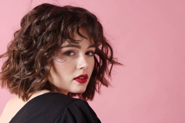 Pembe arka planda dalgalı saç stili olan güzel bir genç kadının portresi. Metin için boşluk