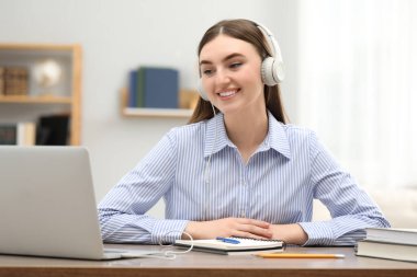 E-öğrenme. İçerideki masada online ders sırasında dizüstü bilgisayar kullanan genç bir kadın.