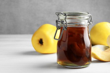 Kavanozda ev yapımı ayva reçeli ve beyaz ahşap masada meyveler, yakın plan. Metin için boşluk