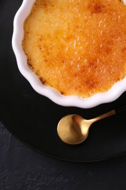Koyu gri desenli masada servis edilen kasedeki leziz creme brulee.