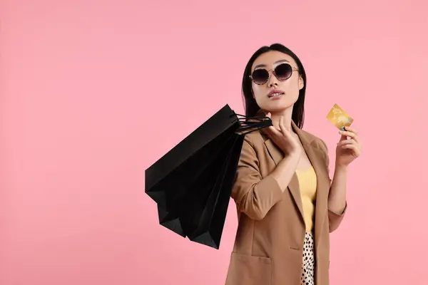 stock image Beautiful woman with shopping bags and credit card on pink background. Space for text