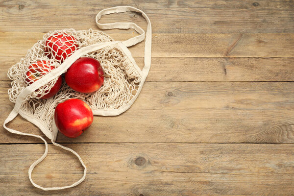 String bag with fresh apples on wooden background, top view. Space for text