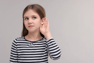Gri arka planda işitme sorunu olan küçük kız, mesaj için boşluk