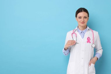 Açık mavi arka planda pembe kurdeleli Mammolog, yazı için yer var. Göğüs kanseri farkındalığı