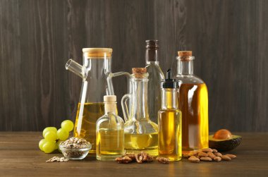 Sebze yağları. Cam şişelerdeki farklı yağlar ve ahşap masadaki malzemeler.