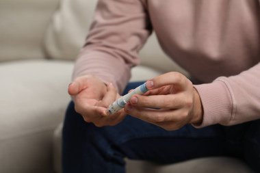 Diyabet testi. Bulanık arka planda kan şekeri seviyesini tükenmez kalemle ölçen adam, yakın plan.