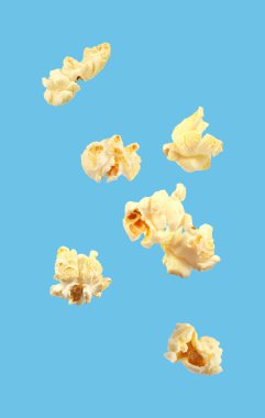 Açık mavi arka planda uçan lezzetli taze patlamış mısır.