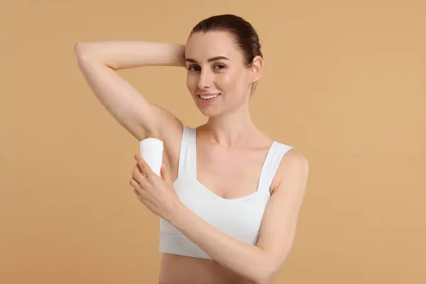 Piękna Kobieta Stosująca Dezodorant Beżowym Tle — Zdjęcie stockowe