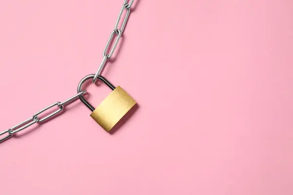 Steel padlock with chain on pink background, top view. Space for text