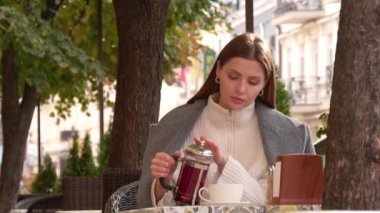 Çekici bir kadın açık kafede sıcak çay dolduruyor, düşük açılı.