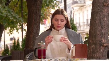 Dışarıdaki kafede sıcak içecek içen çekici bir kadın.