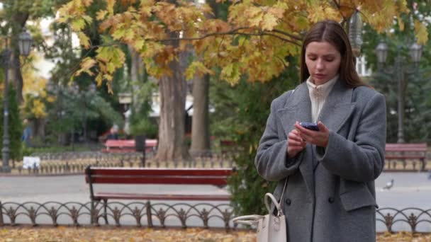 穿着时髦灰色外套的迷人女人在户外用手机 — 图库视频影像