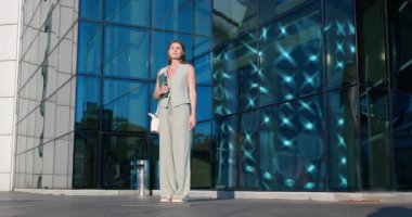 Tabletli güzel genç bir kadın açık havada taksiye biniyor, düşük açılı.