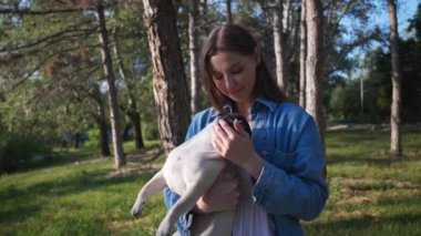 Güneşli bir sabahta sevimli köpeğiyle parkta mutlu bir genç kadın. Kamera hareket ediyor, yavaş çekim etkisi