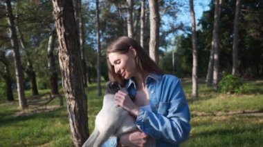 Güneşli bir sabahta sevimli köpeğiyle parkta mutlu bir genç kadın. Kamera hareket ediyor, yavaş çekim etkisi