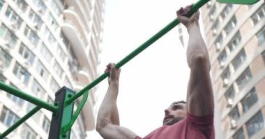 Spor salonunun önünde barfiks çeken atletik bir adam.