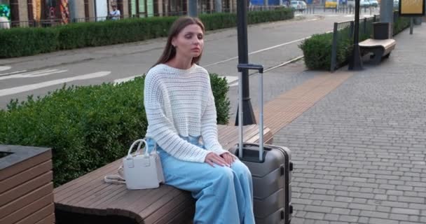 Piękna Młoda Kobieta Siedzi Ławce Pomocą Telefonu Podczas Oczekiwania Taksówką — Wideo stockowe