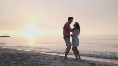 Gün batımında deniz sahilinde dans eden güzel bir çift. Yavaş çekim etkisi