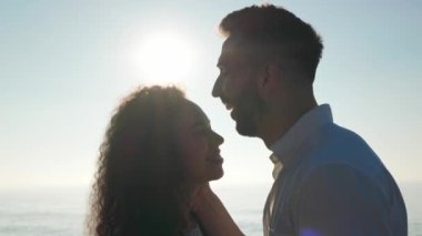 Gün batımında deniz sahilinde yürüyen güzel bir çift, alçak açılı bir manzara. Kamera izleme, düşük hareket efekti