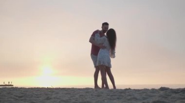 Gün batımında deniz kenarında dans eden güzel bir çift.