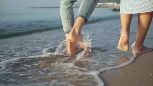 カップルは クローズアップで海浜で裸足を歩いています 前方に移動するカメラ スローモーション効果 — ストック動画