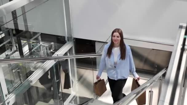 Glückliche Junge Frau Mit Papiereinkaufstüten Kommt Treppe Einkaufszentrum Hoch Zeitlupe — Stockvideo