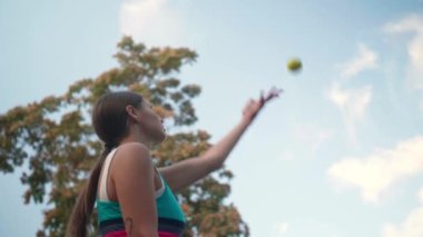 Spor kıyafetli bir kadın açık havada tenis oynuyor. Düşük açılı. Yavaş çekim etkisi
