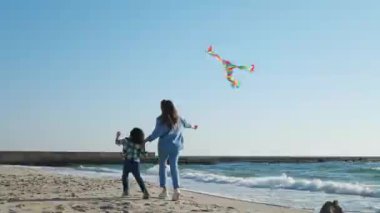 Uçurtmalı anne ve oğlu sahilde koşuyor. Kamera izleme