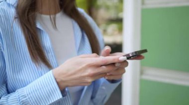 Dışarıda yürürken cep telefonu kullanan bir kadın, yakın plan. Kamera geri gidiyor, yavaş çekim efekti