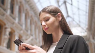 Binaların yanında cep telefonu kullanan güzel bir kadın. Düşük açılı.