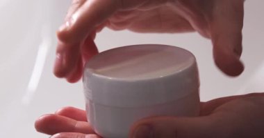 Kadın içeride cilt kremi kavanozunu açıyor, yakın plan.