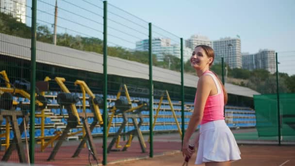 裁判所でテニスをするスタイリッシュなスポーツウェアで幸せな女性 スローモーション効果 — ストック動画