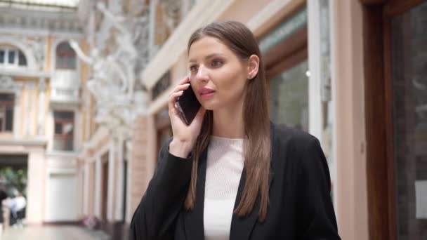 一个情绪化的年轻女人在大楼附近用电话交谈 视角很低 相机左移 慢动作效果 — 图库视频影像