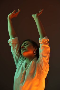 Renkli arka planda, neon ışıklı güzel bir genç kadının portresi