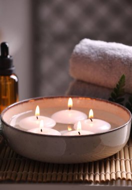Spa kompozisyonu. Kavanozda mumlar, havlular ve masa üzerinde gerekli yağ şişesi, yakın plan.