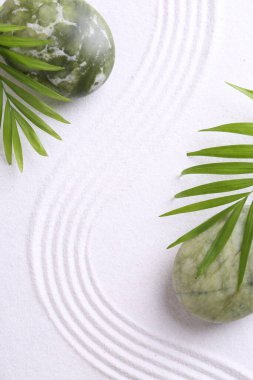 Zen konsepti. Taşlar, yapraklar ve desenler beyaz kumlarda, düz yatıyordu.