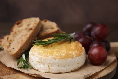 Lezzetli fırında camembert, bir parça ekmek, üzümler ve biberiye, yakın plan.