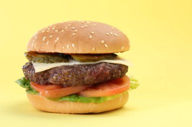 Sarı arka planda lezzetli köfteli burger, yakın plan.