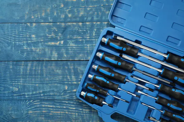 Mavi ahşap masadaki açık alet çantasında bir tornavida seti. Metin için boşluk
