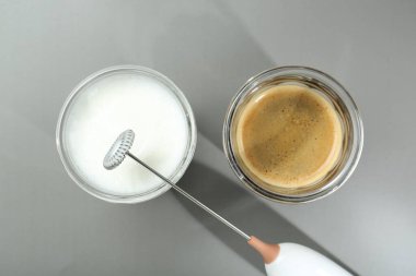 Mini mixer (milk frother), whipped milk and coffee in glasses on grey background, flat lay clipart