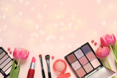 Farklı makyaj ürünleri ve pembe arka planda güzel lale çiçekleri. Mesaj atmak için yer var. Bokeh etkisi